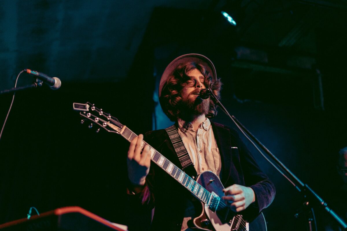 White male playing a left-handed guitar.