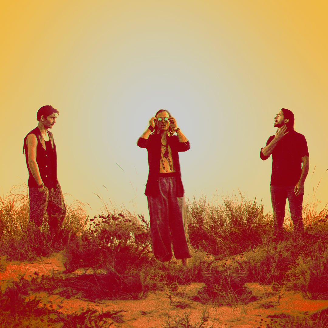 Three men wearing black clothing in a desert environment.