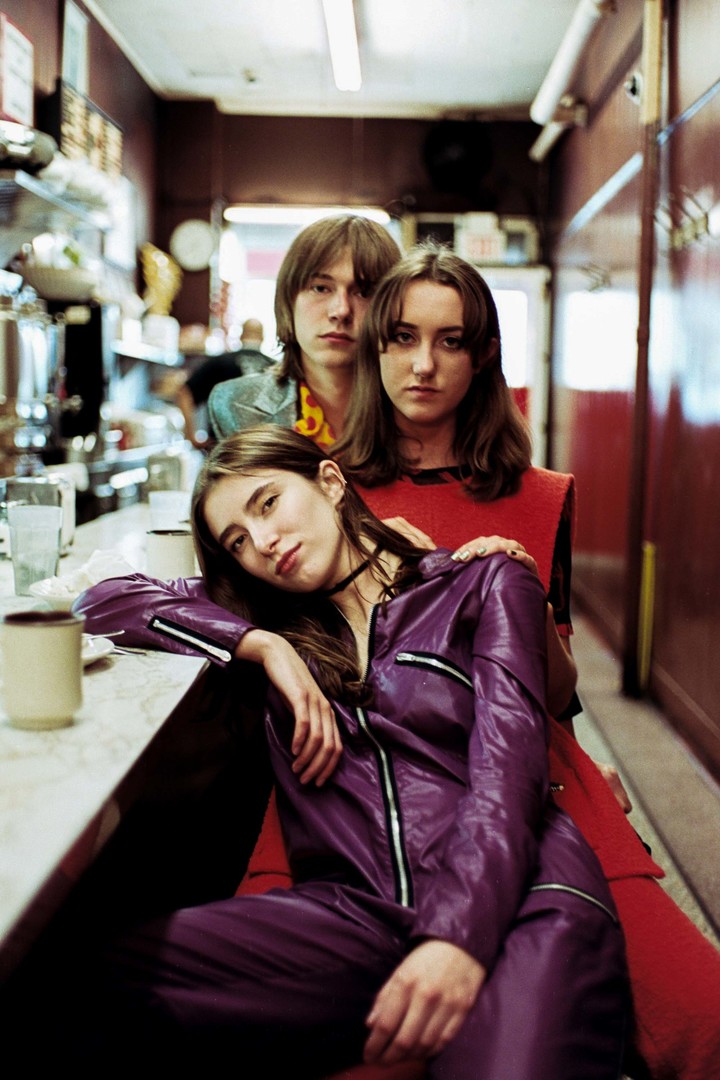 Photograph of Moonwalks. Two women and a man pose for a photo whilst sitting at a diner counter.